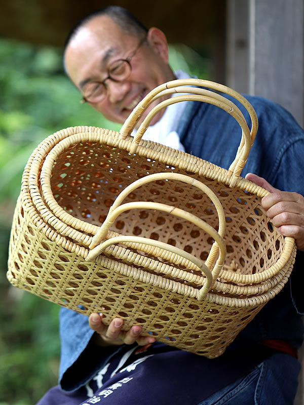 白竹八ツ目手提げ籠の三個入りを持つ竹虎四代目（山岸義浩）